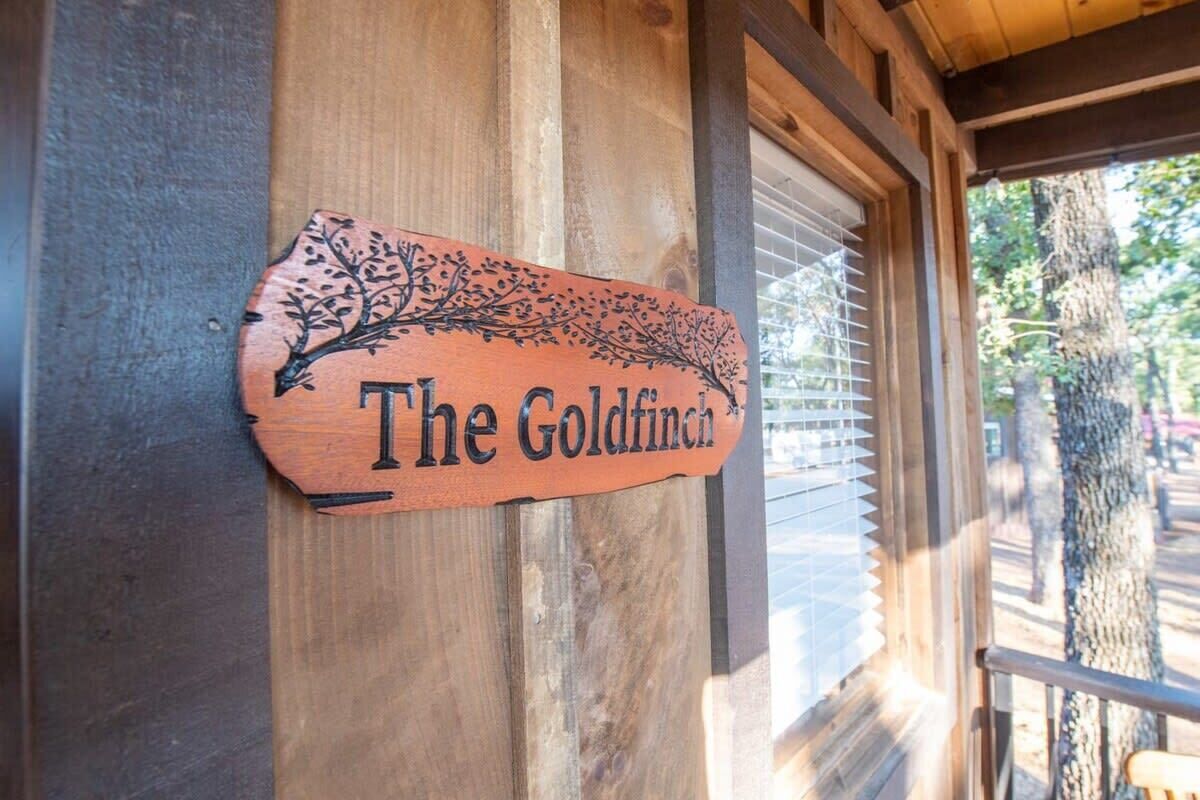 A wooden sign with the text "The Goldfinch" and a tree branch design.