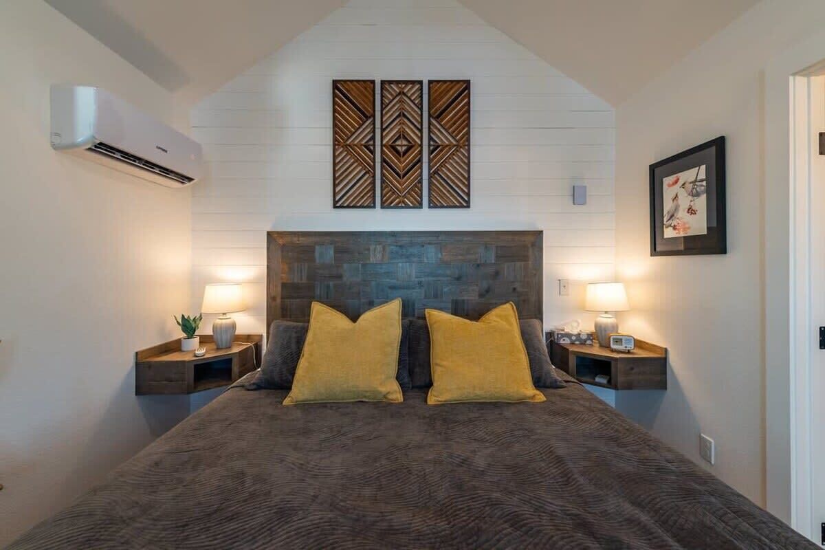 A bedroom with a stone headboard, two bedside lamps, and a framed artwork on the wall.