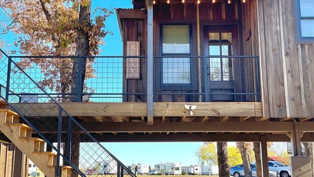 Una cabaña de madera con un balcón, una escalera y un letrero que dice 'REX LAX'.