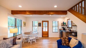 A spacious living area with a dining table, sofas, and a kitchen in the background. - The Nuthatch Cabin (15 MIN to Magnolia & Baylor) (Elm Mott)