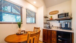 A compact kitchen with a wooden dining table, a black refrigerator, and a microwave on the countertop. - The Sparrow Treehouse 15 MIN to Magnolia & Baylor (Elm Mott)