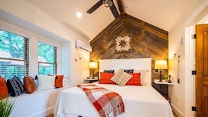 A bedroom with a large bed, two bedside tables, a ceiling fan, and a wooden accent wall. - The Sparrow Treehouse 15 MIN to Magnolia & Baylor (Elm Mott)