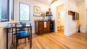 Una cucina moderna con mobili in legno, un'area pranzo con tavolo e sedie, e vista sul bagno adiacente.