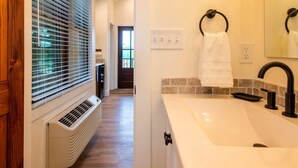 Un bagno moderno con un lavandino bianco, un rubinetto nero e un appendi asciugamani.