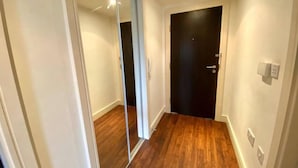 Een gang met houten vloer, een schuifdeur van glas en een zwarte deur.