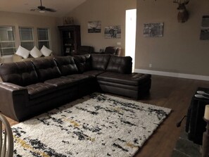 Relax in this inviting living room with a large L-shaped sofa, patterned rug, and framed artwork.