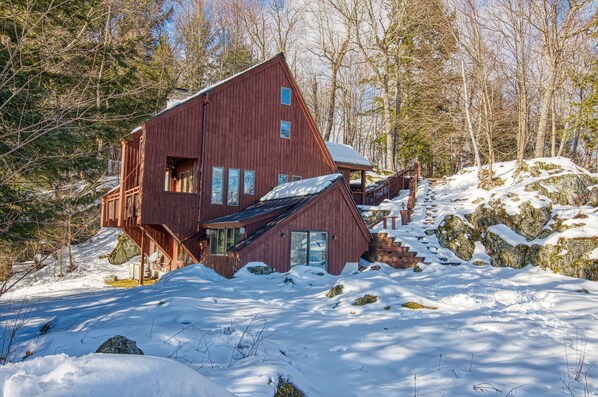 Une cabane en bois, dotée d’un toit en pente, entourée d’un paysage enneigé et d’arbres.