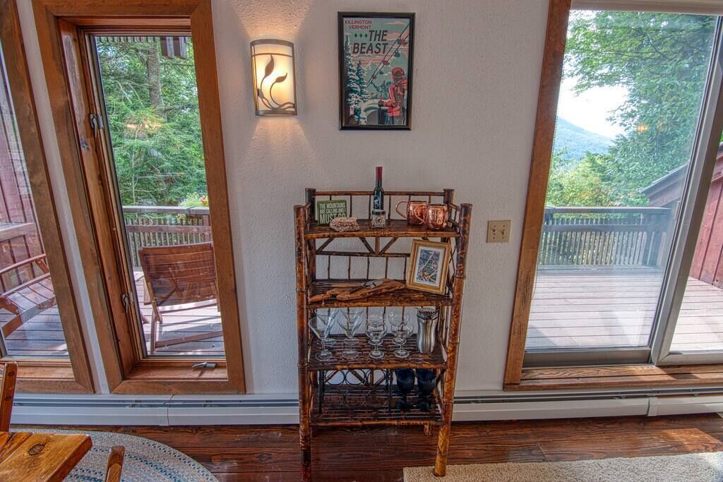 A wooden shelf with glassware and a framed picture, a wall-mounted light, and a poster on a wall.