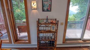 A wooden shelf with glassware and a framed picture, a wall-mounted light, and a poster on a wall.
