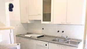 Een moderne keuken met witte kasten, een roestvrijstalen spoelbak en een Bosch vaatwasser.