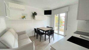 Eine moderne Küche mit Essbereich, einer Couch und einem an der Wand befestigten Fernseher.