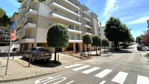 Ein mehrgeschossiges Wohngebäude mit Balkonen, einem Parkplatz und einer Fußgängerüberweg.