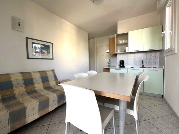 Un espacio habitable pequeño con sofá, mesa de comedor y kitchenette.