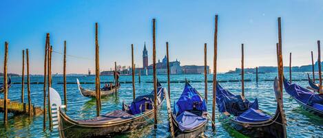 Gondolas amarradas en un muelle con un paisaje urbano al fondo.