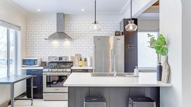 Een moderne keuken met een centraal eiland, roestvrijstalen apparatuur en barkrukken.