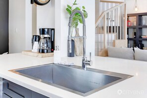Modern kitchen with sleek sink and faucet, minimalist design, and a cozy coffee station.