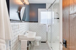 A modern bathroom with a white sink, toilet, and shower area. - Strathcona. Sleeps 6. Steps from Whyte Ave. (Edmonton)
