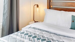 Een opgemaakt bed met beddengoed met een patroon, een bedlampje en een houten hoofdbord.
