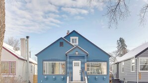 Een blauw huis met een witte deur en ramen, een schoorsteen en een schotelantenne.