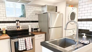 Une cuisine moderne équipée d’une cuisinière en acier inoxydable, d’un four encastré, d’un réfrigérateur et d’un lave-linge.