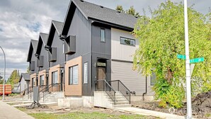 Un immeuble résidentiel moderne doté d’une architecture originale, caractérisé par de nombreux toits à pignons et un escalier imposant menant à l’entrée.