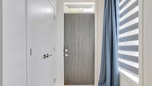 Une pièce avec une armoire blanche, une porte grise et une fenêtre ornée de rideaux bleus.
