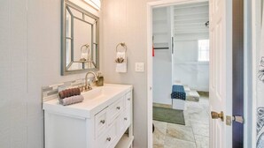 A bathroom with a white vanity, a large mirror, and a towel rack. - Pineapple Loft - Downtown Hilo wAC (Hilo)
