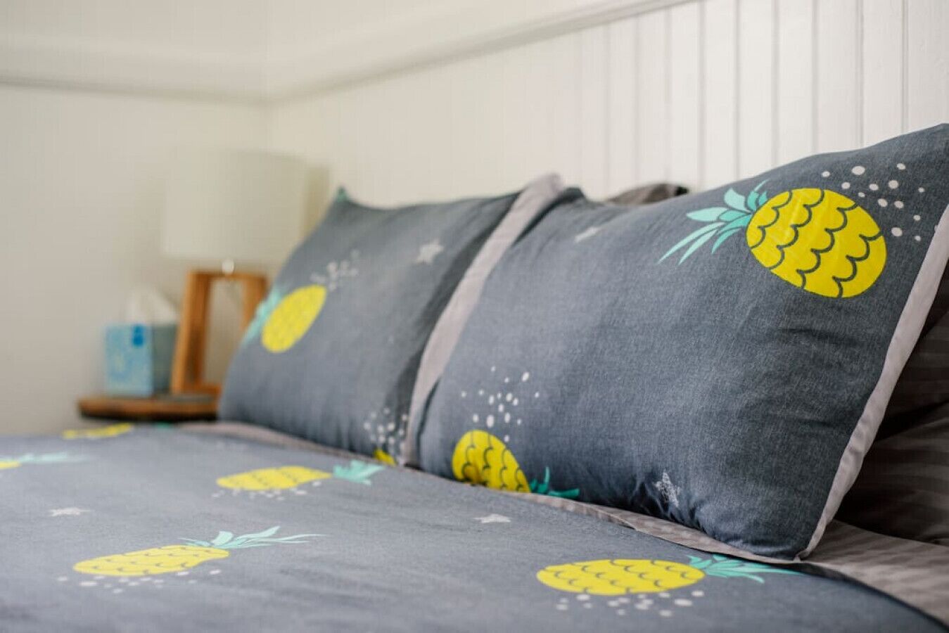 A bed with grey bedding featuring pineapple patterns.