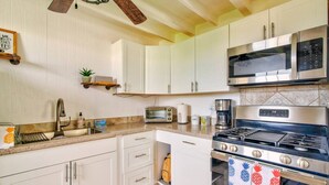A kitchen with white cabinets, a stainless steel microwave, a gas stove, and a toaster. - Pineapple Loft - Downtown Hilo wAC (Hilo)