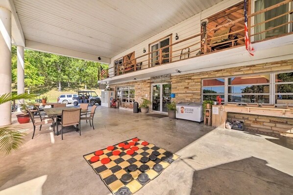 An outdoor patio area with a checkered floor, tables, chairs, and a view of a building with a restaurant named "The Big Red Barn".