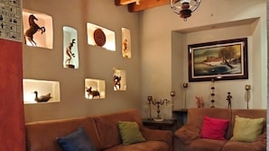 A living room with a brown sofa, a smaller armchair, and a painting on the wall.