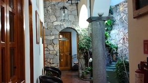 A corridor with wooden beams, stone walls, and a door labeled 'Lounge.'