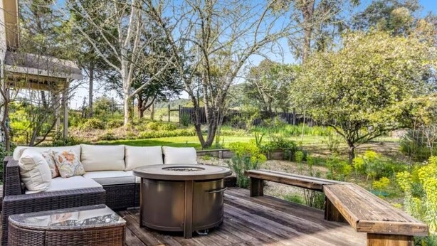 An outdoor patio with a wicker sofa, a round table, and a bench.