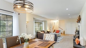 A spacious living room with a large wooden dining table, comfortable seating, and a staircase leading to an upper level.