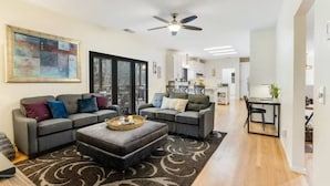 A modern living room with a sectional sofa, a coffee table, and a dining area with a small table and chairs.