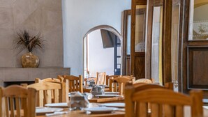 A dining area with wooden tables and chairs, a vase with dried plants, and a mirror on the wall. - Hotel Meson de Isabel (Querétaro)