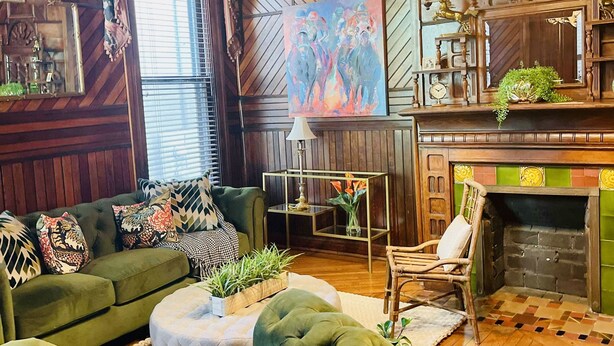Una sala de estar acogedora con un sofá verde, techo de madera y chimenea.
