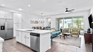 A modern kitchen with white cabinetry, a built-in dishwasher, and a large island with a sink. - Townhome with Screened Pool, Kids Bedrooms, Near Attractions (Kissimmee)