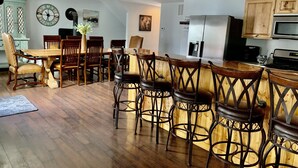 Uma cozinha moderna com armários de madeira, uma geladeira de aço inoxidável e um balcão com banquetas.