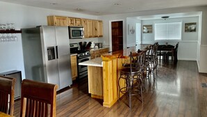 Cozinha com armários de madeira, eletrodomésticos de aço inoxidável e um espaço bar com banquetas.