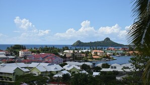 Uma cidade costeira com edifícios coloridos, uma colina imponente ao fundo e um céu azul límpido.
