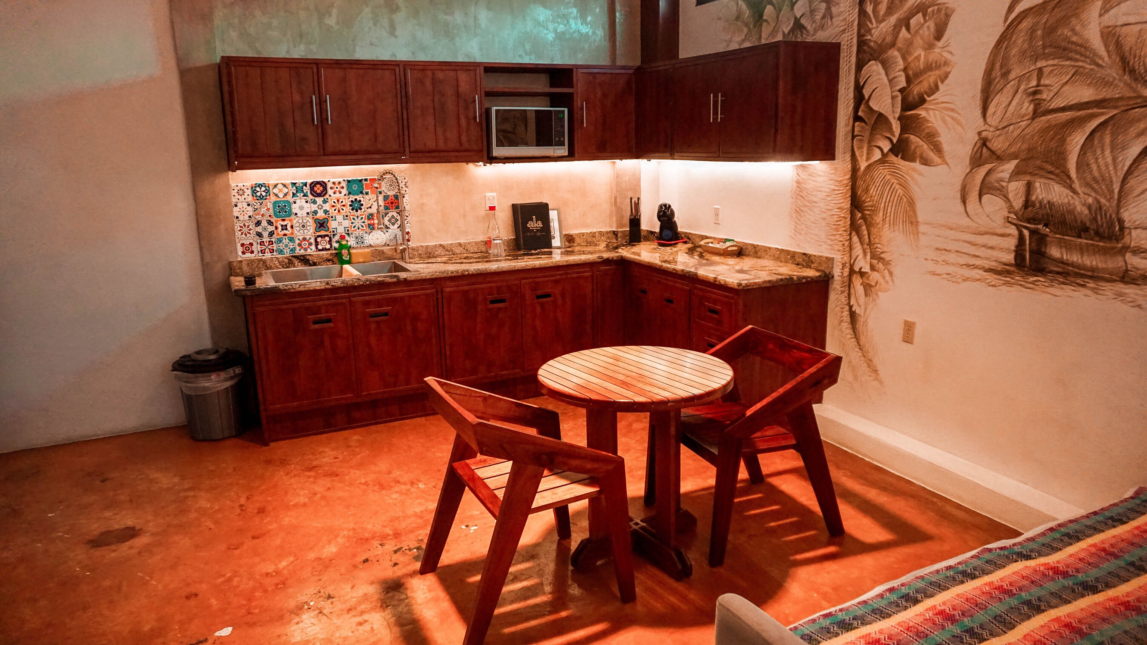 A compact kitchen with wooden cabinets, a microwave, and a tiled backsplash.