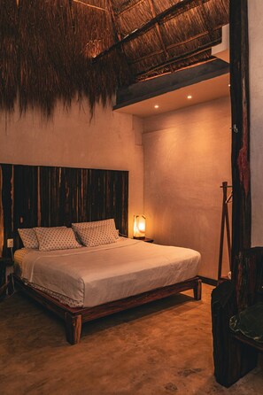 A bedroom with a wooden bed, a nightstand, a lamp, and a rustic ceiling. - ALA Residencias (Chetumal)