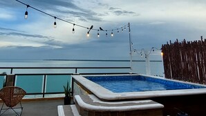 A rooftop pool area with a view of the sea, string lights, and a wooden fence. - ALA Residencias (Chetumal)