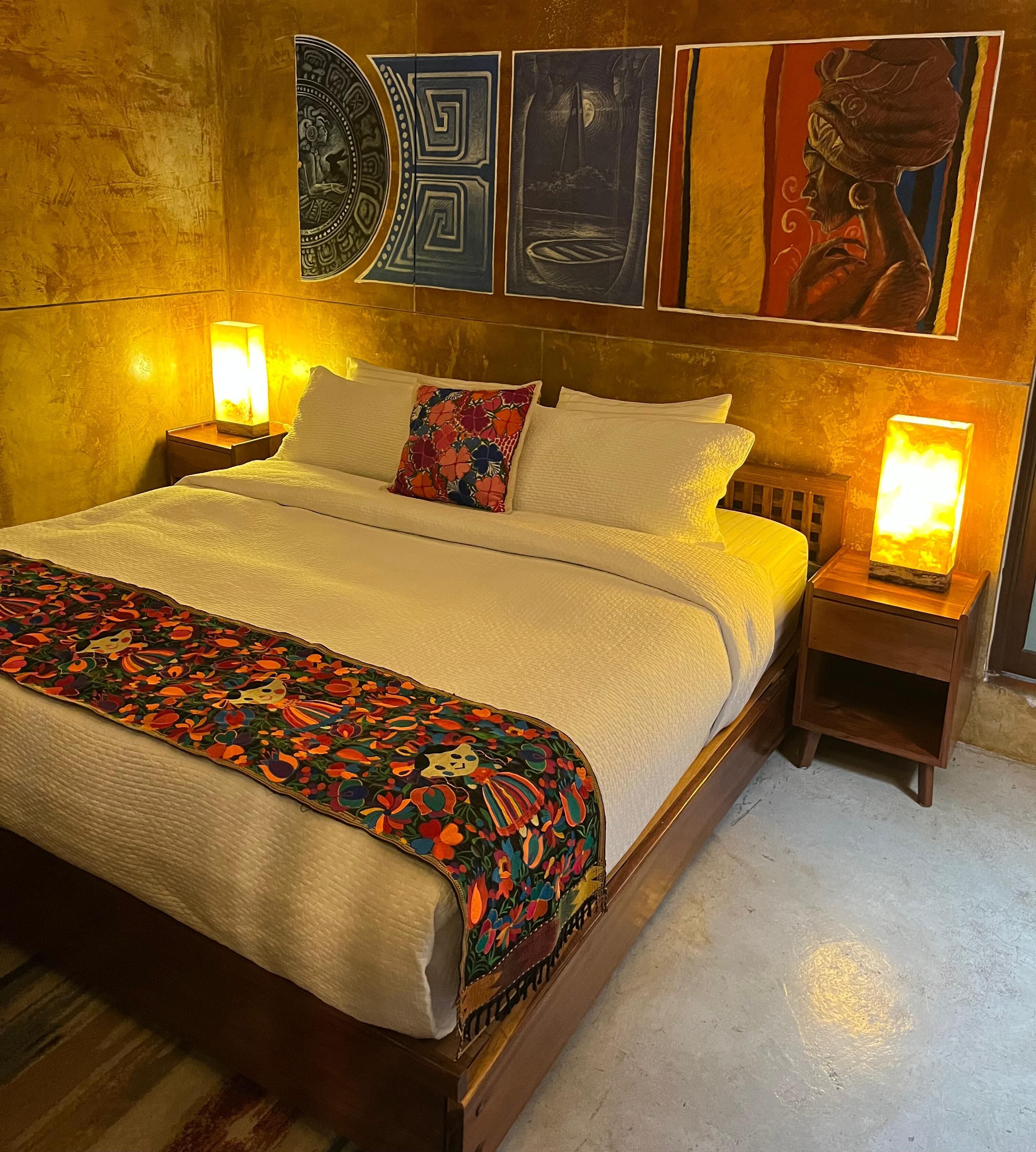 A bed with a floral bedspread, two pillows, and two bedside lamps.