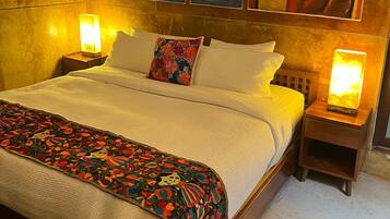 Una cama con colcha estampada, dos almohadas y dos lámparas de noche.