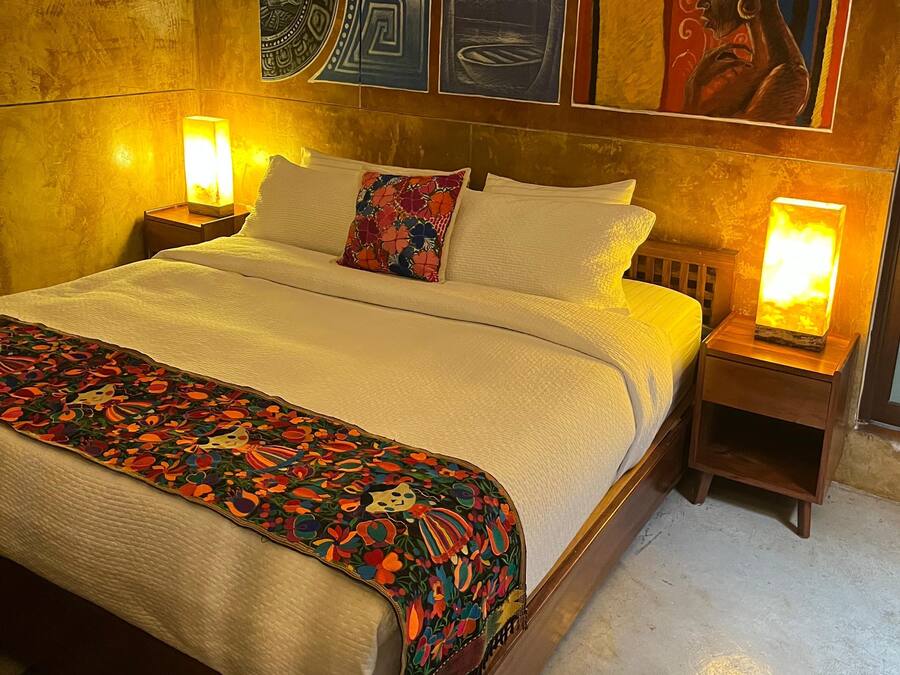 Una cama con colcha estampada, dos almohadas y dos lámparas de noche.