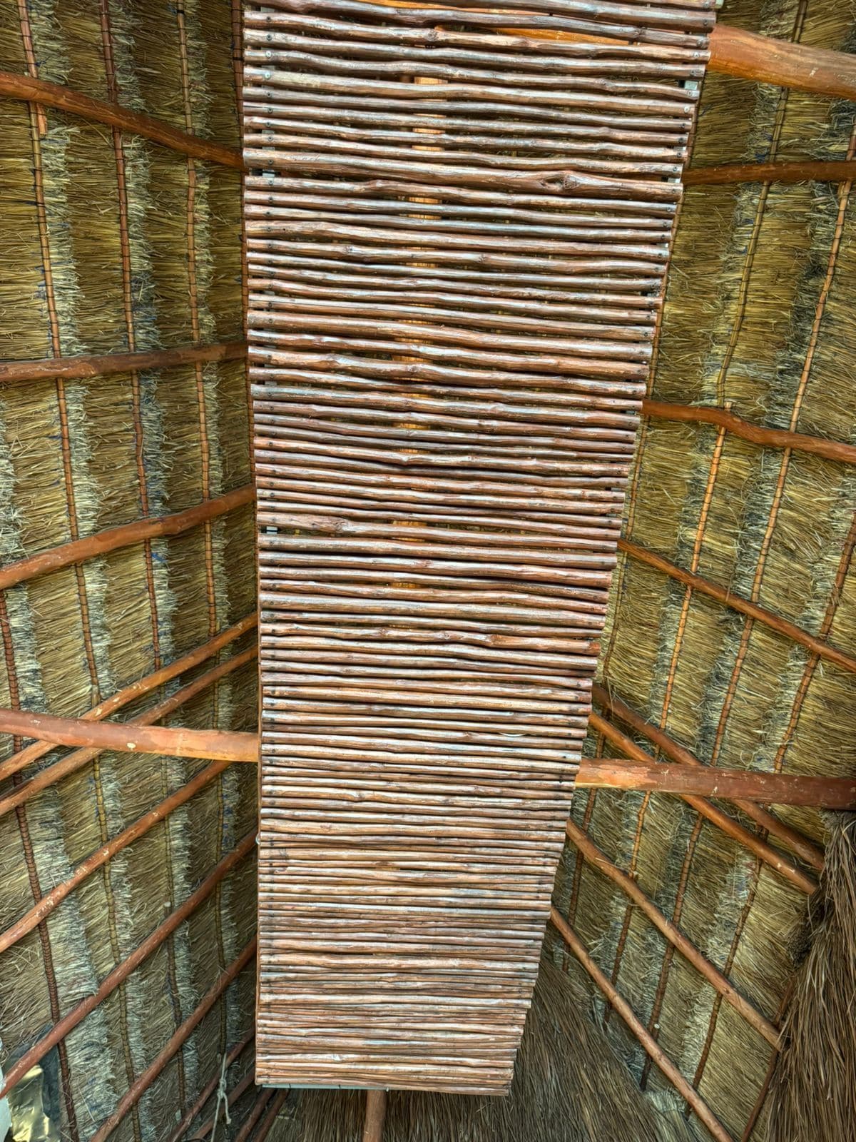 A room with a thatched roof and wooden beams.
