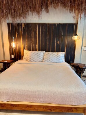 A bed with a wooden headboard, two bedside lamps, and a patterned pillow. - ALA Residencias (Chetumal)