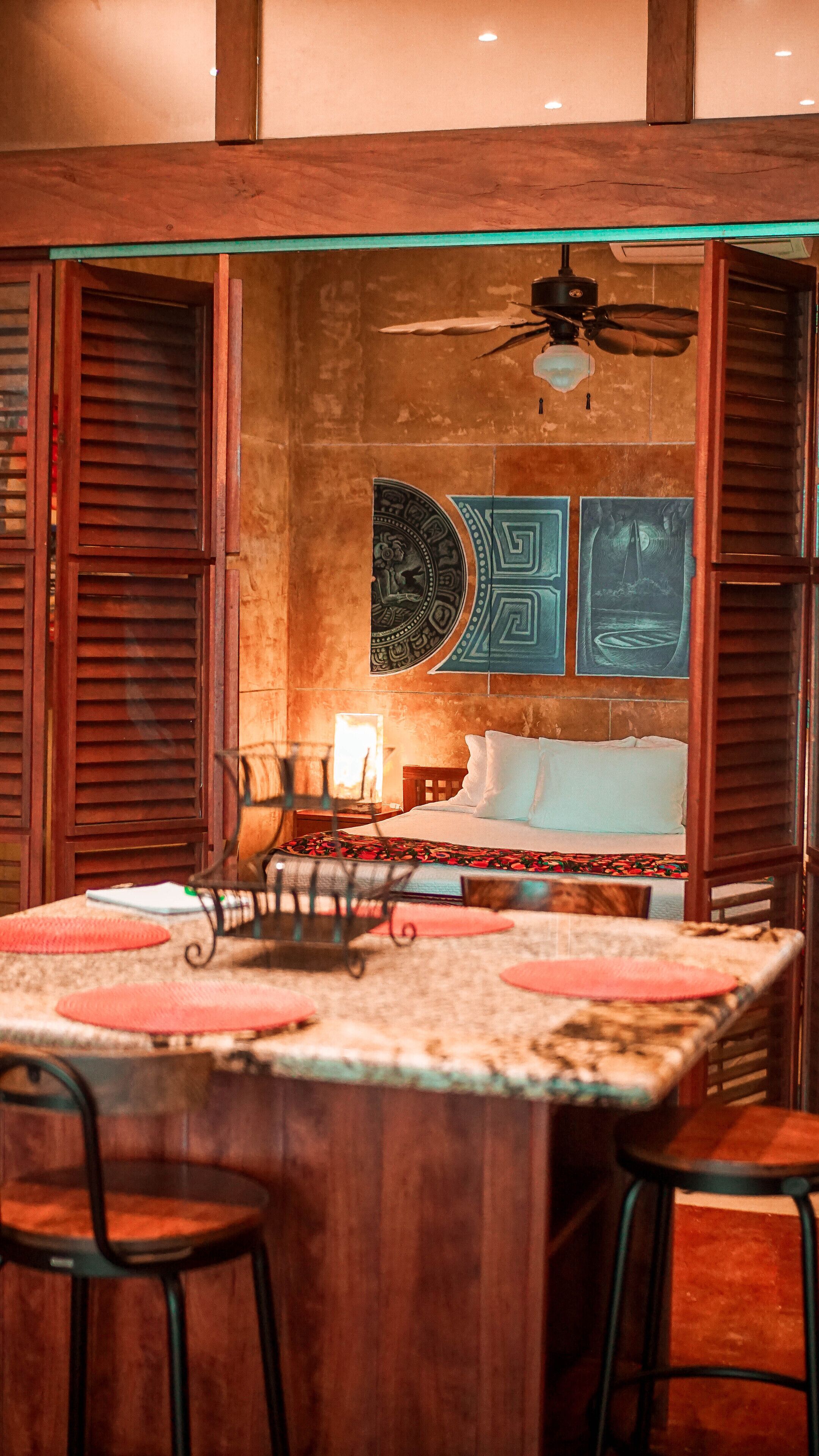 Una habitación con una cama, una mesa con sillas y un ventilador de techo.